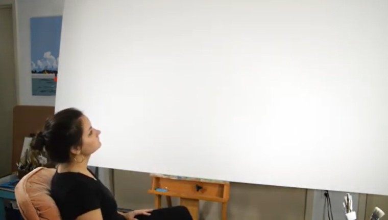 Elizabeth Barenis sits in front of a blank white canvas.