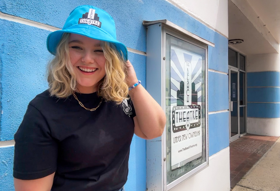 A woman wears a bucket hat that reads The Beach Theatre.