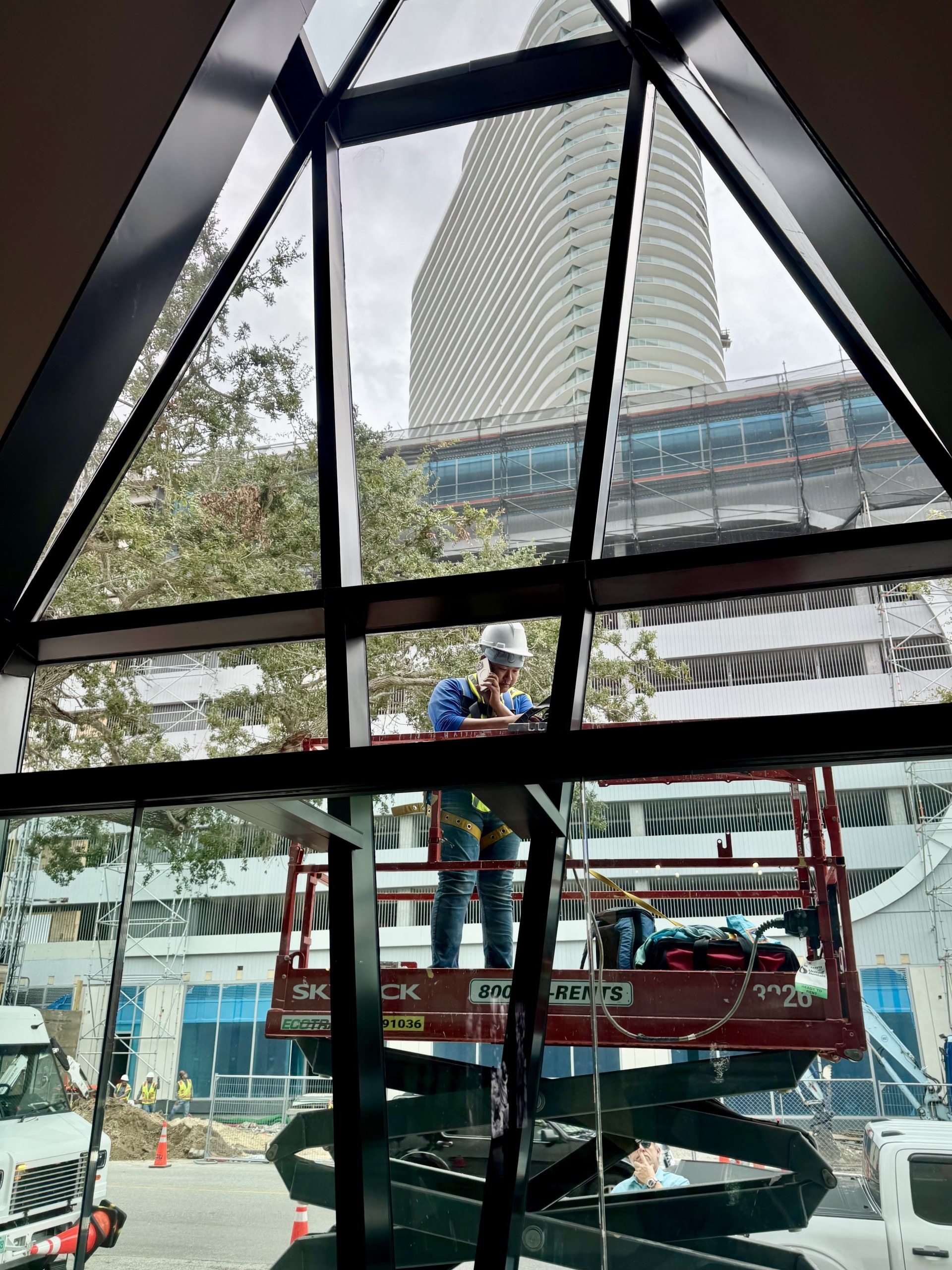 A man on scaffolding is seen though a triangular window.