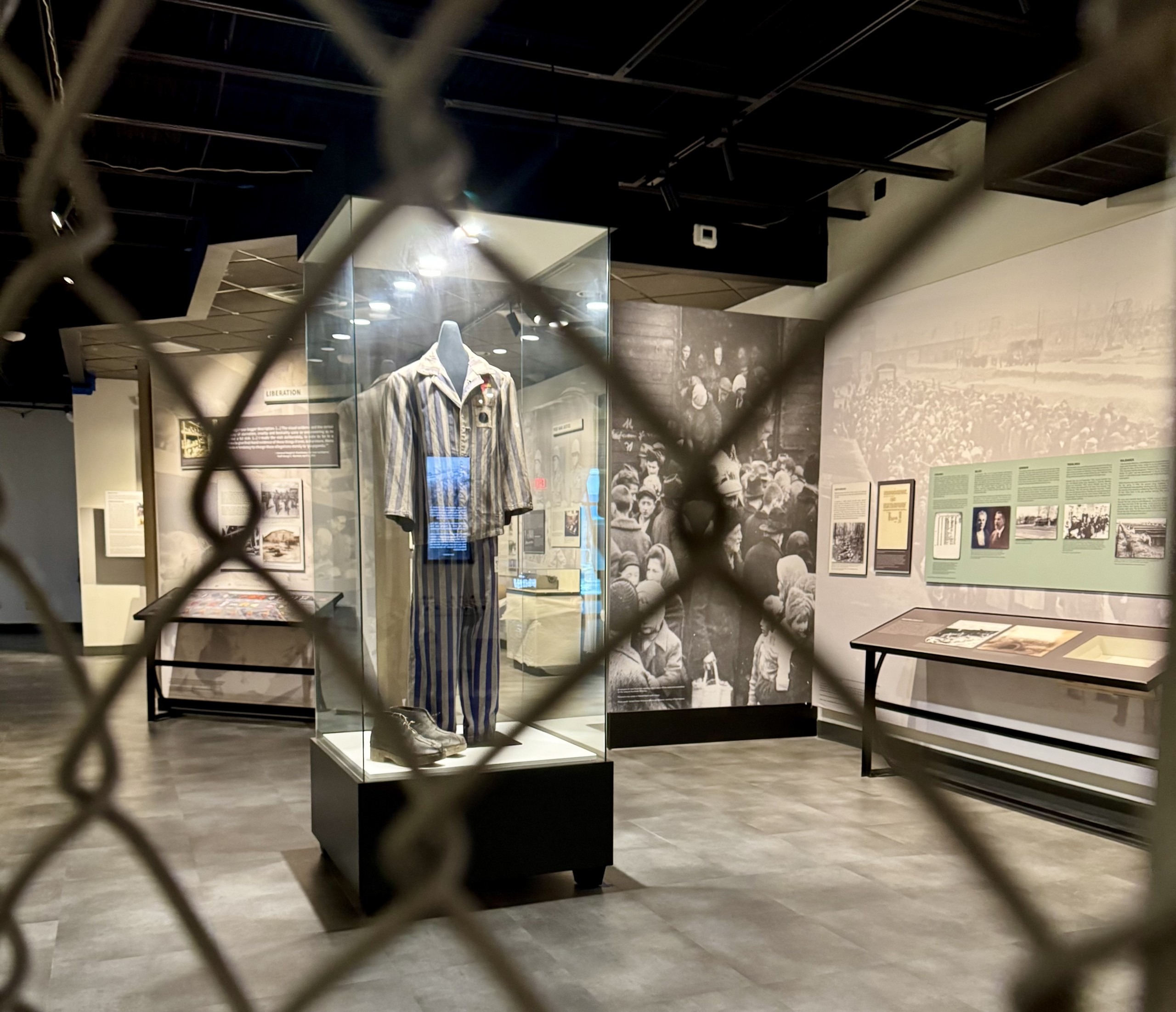 A historical museum displays items from the Holocaust, pictured through a chain link fence.