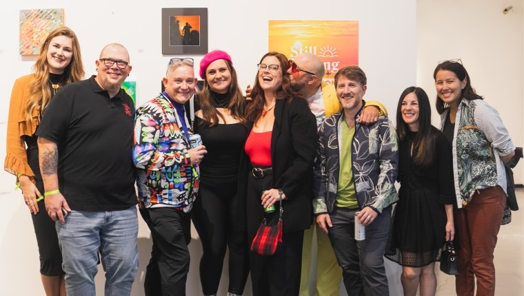 People pose in front of artwork.