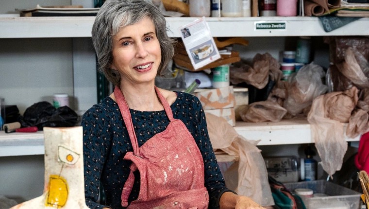 A woman posing with her ceramic artwork.
