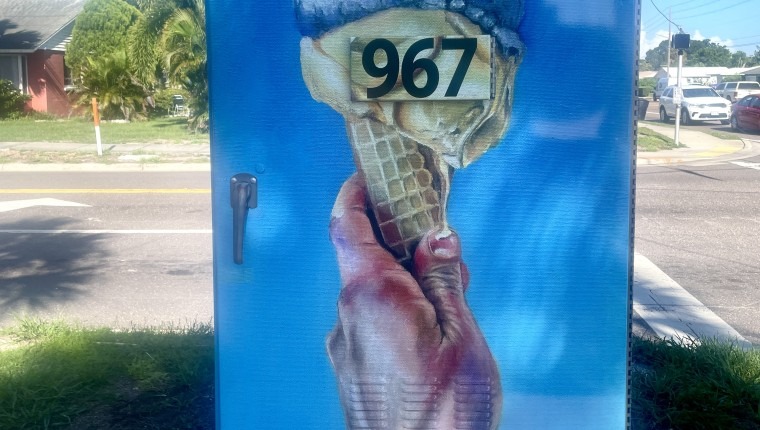 A signal box is decorated with a hand holding an ice cream cone.