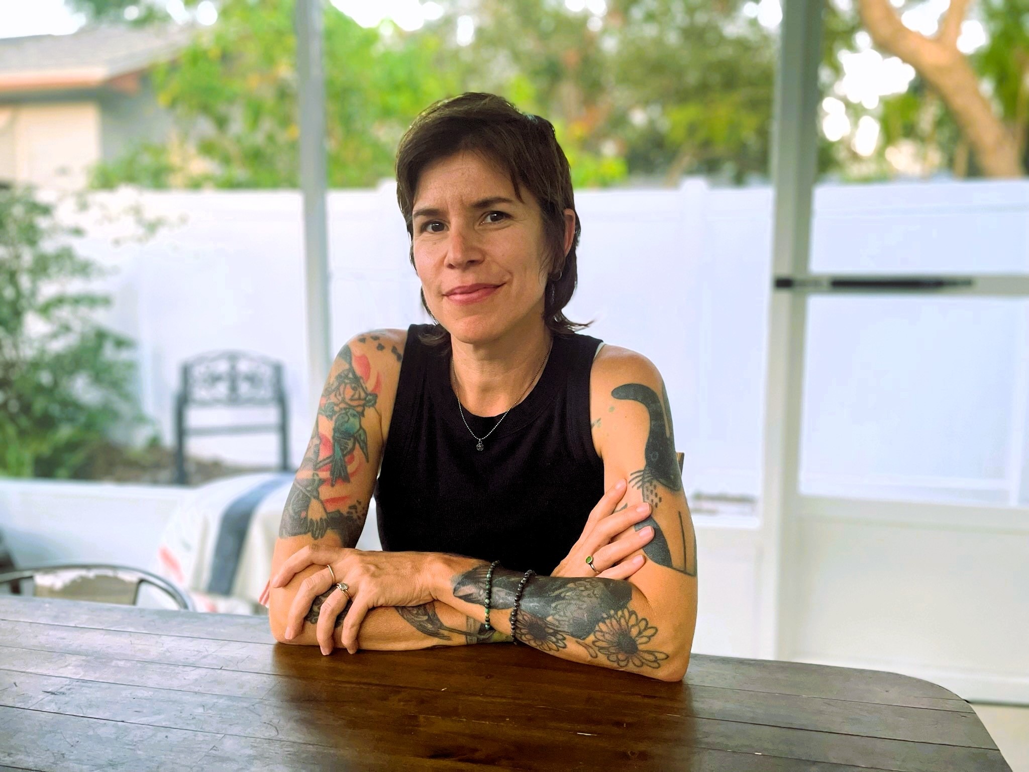 A woman in a black shirt poses at a table.